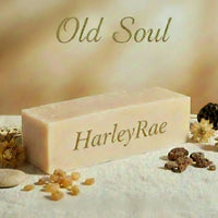 Bar of soap with 'Old Soul' and 'HarleyRae Wellness' branding on a textured surface with decorative elements.